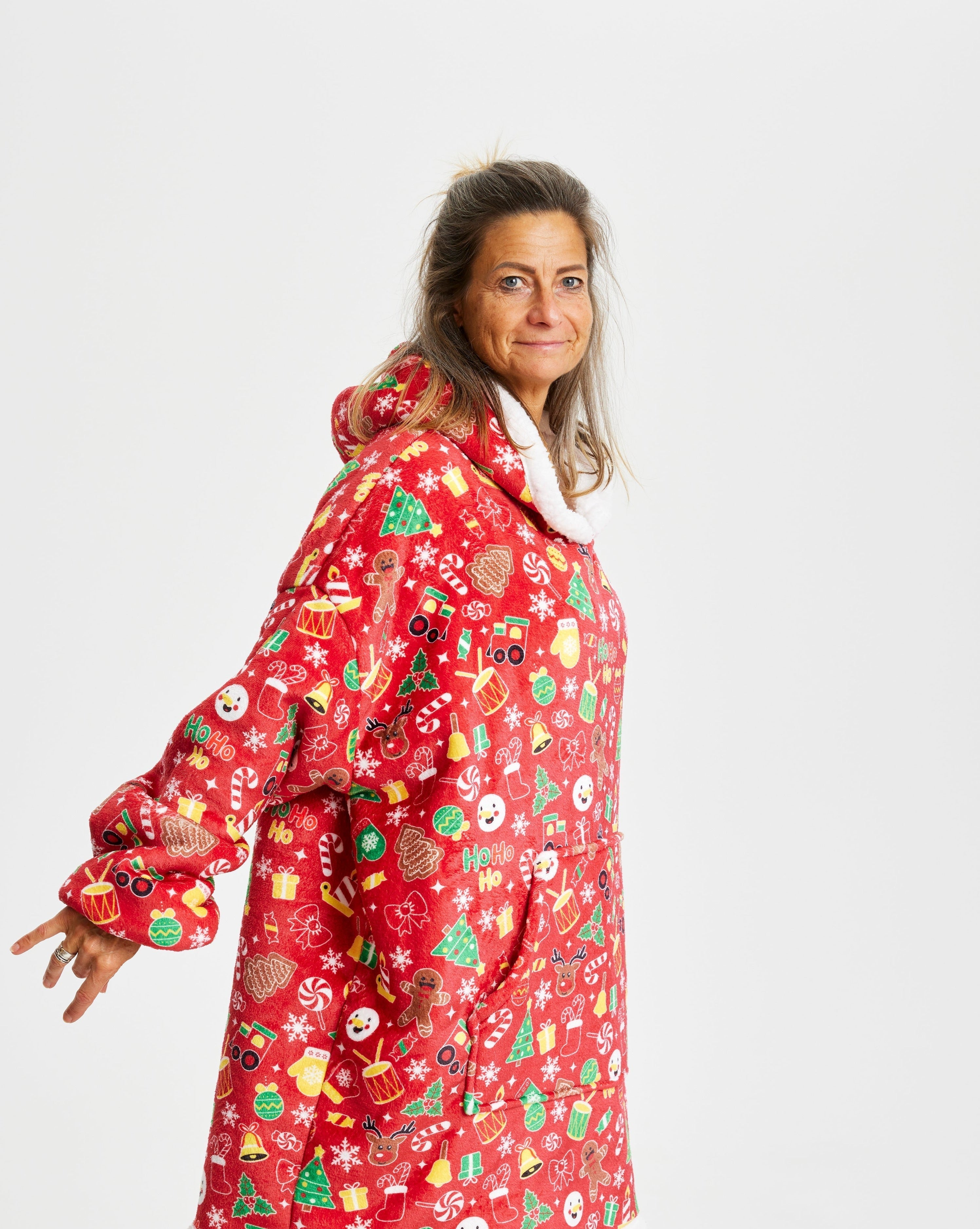 En kvinna som bär en röd julig huvtröja med julmönster.